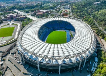 Pionowy widok z drona na Stadio Olimpico w Rzymie w słoneczne południe, ukazujący jaskrawą zieleń murawy i jasny dach