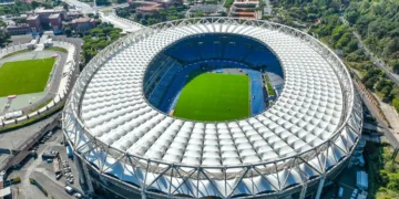 Pionowy widok z drona na Stadio Olimpico w Rzymie w słoneczne południe, ukazujący jaskrawą zieleń murawy i jasny dach