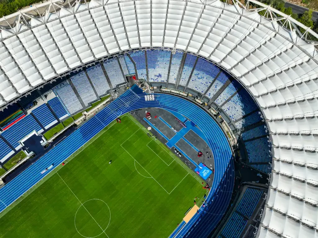 Symetryczny układ pustych trybun Stadio Olimpico w Rzymie w pełnym słońcu, ujęcie z lotu ptaka.
